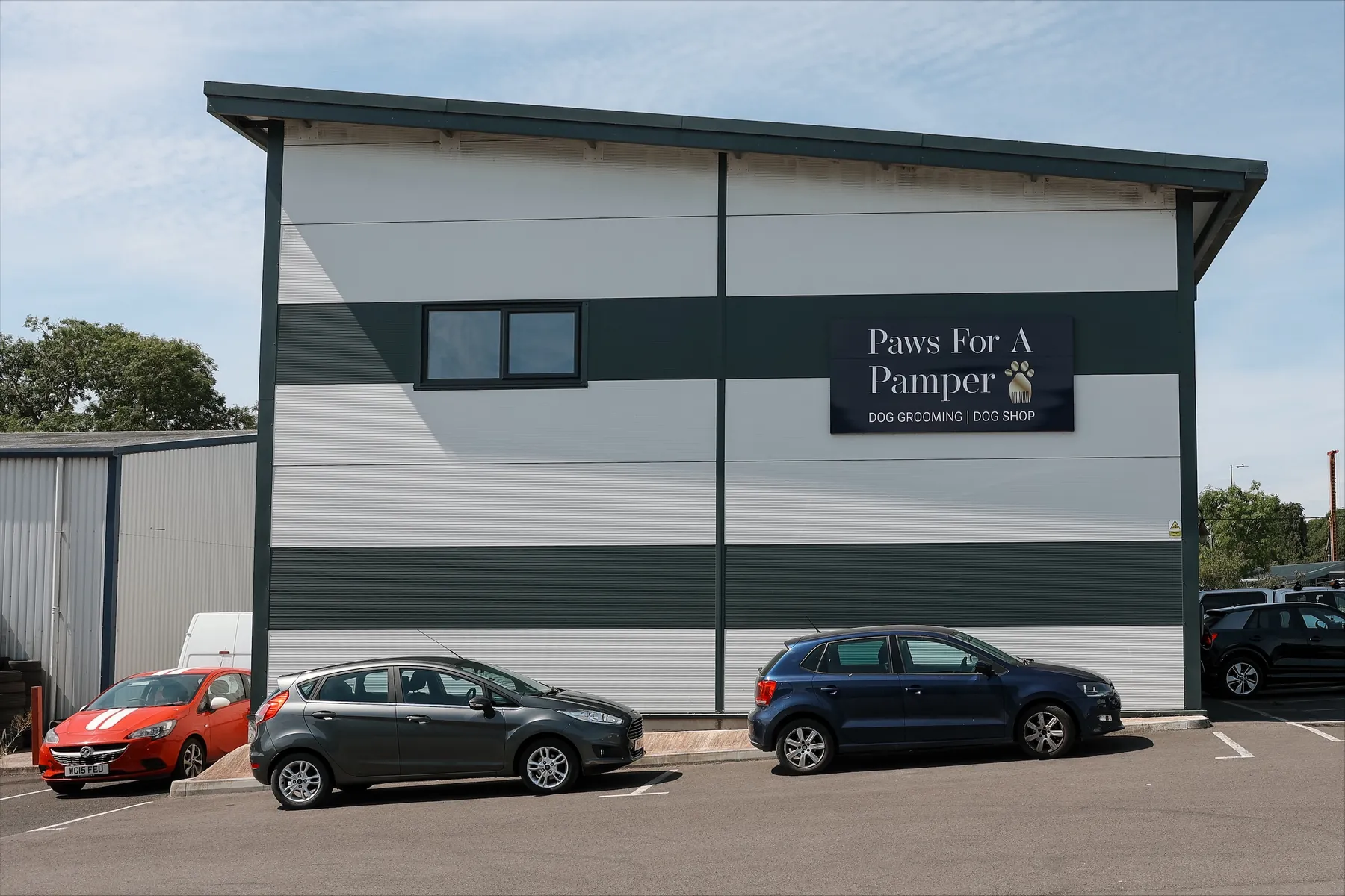 The Paws For A Pamper unit from outside, with the salon sign on the front and cars parked in front