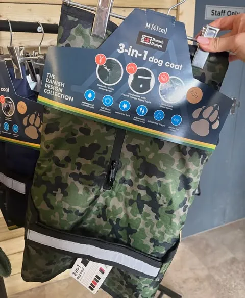 A camouflage Danish Design 3-in-1 dog coat held up on its hanger