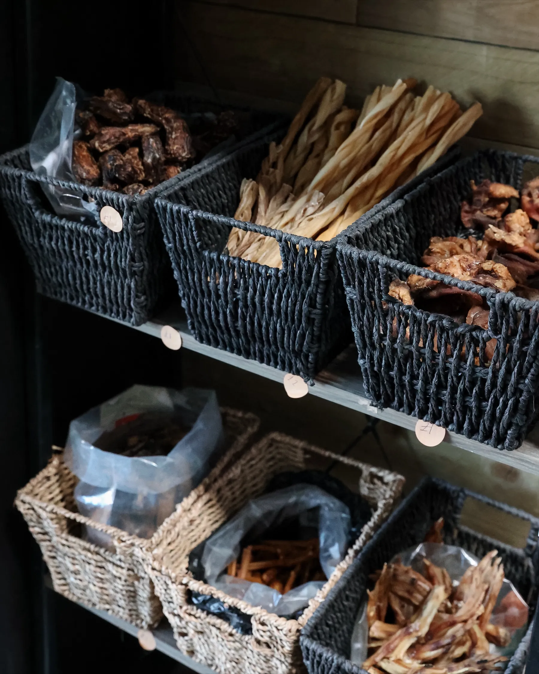 Baskets of natural dog treats on the shop shelves: dried fish, chews and jerky